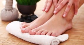 A woman drying her sweaty feet with a towel